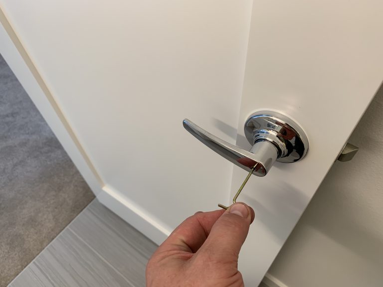 a person inserting a small key into a hole inside a doorknob