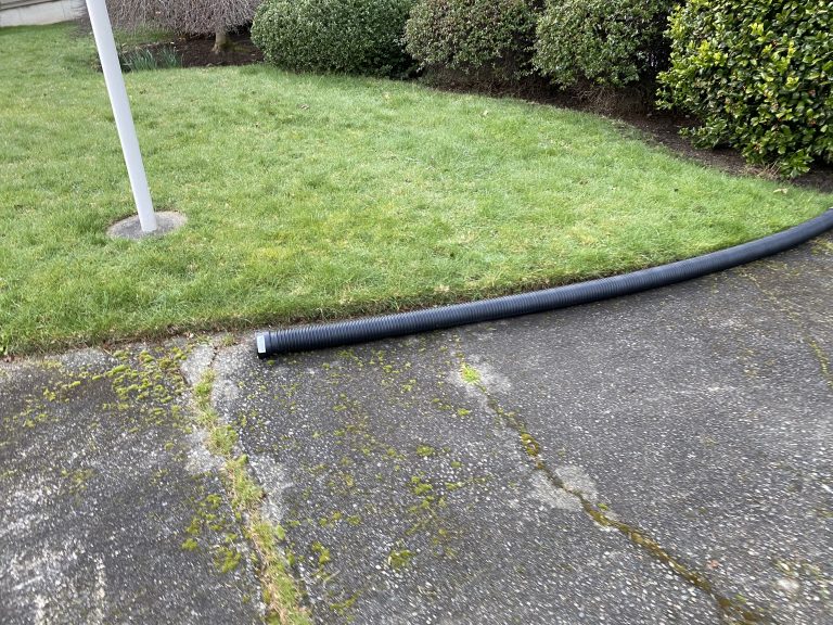 a tube connected to a downspout that ends in the middle of a driveway