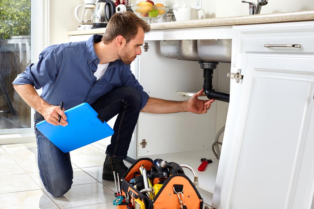 A home inspector checking under the sink