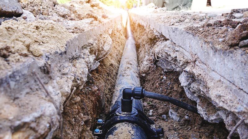 An exposed sewer line sits visible in the sun.