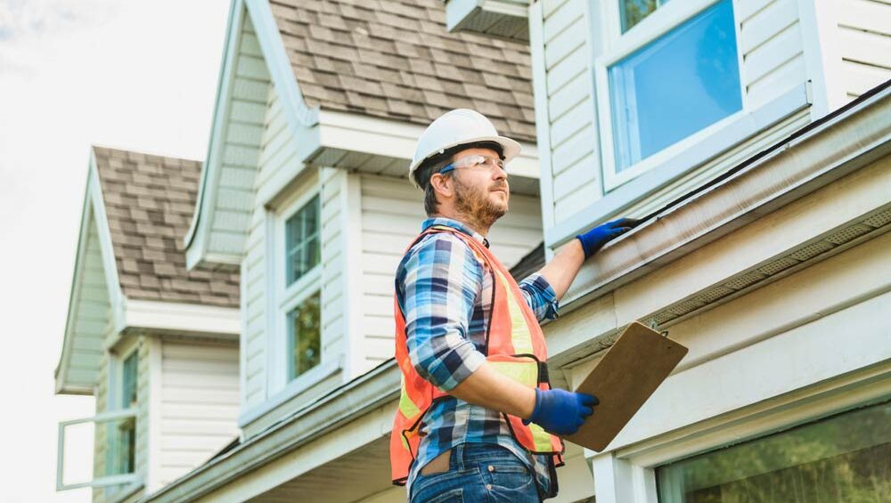 A home inspector checks the gutters and roof of a home.