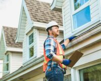 A home inspector checks the gutters and roof of a home.